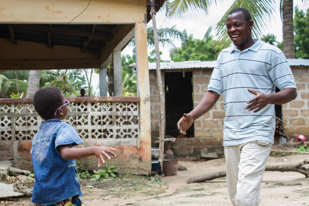 A child reaching toward a family member after cataract surgery in rural Togo