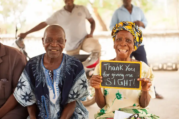 African couple rejoicing and holding a sign that says Thank you for giving me sight African couple rejoicing and holding a sign that says Thank you for giving me sight