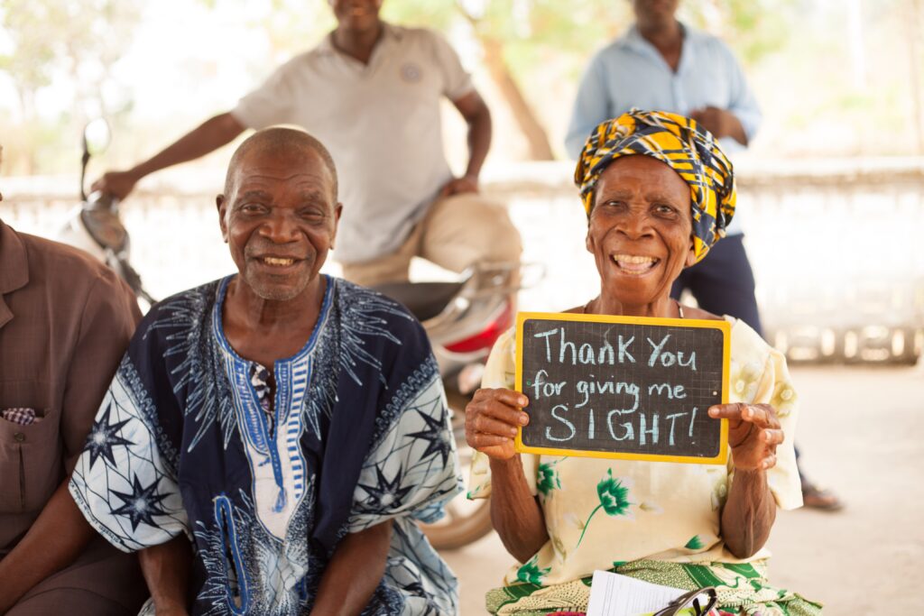 Woman holding a thank-you sign after receiving sight-restoring surgery in Togo