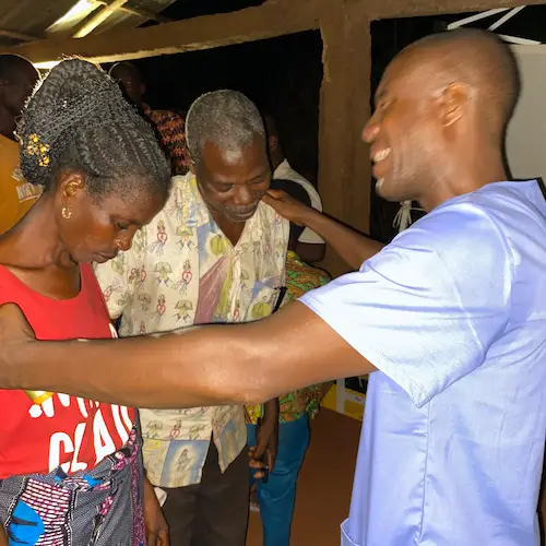Sight.org staff member praying with African couple after cataract surgery